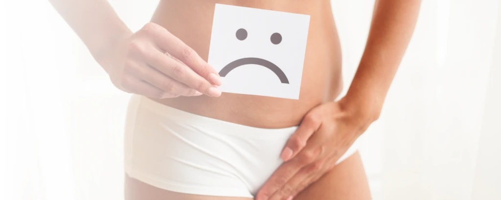 Person fasst sich in den Schritt und zeigt traurigen Smiley